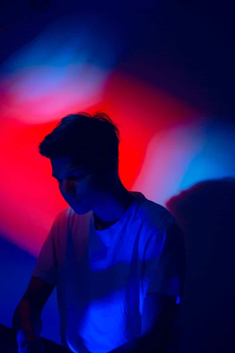 photo of man wearing white shirt with red and blue light background